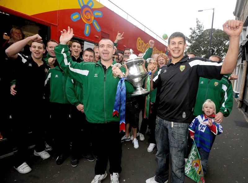 Cougars coach Barry Eaton and skipper James Feather take the trophy on board the open-top bus.