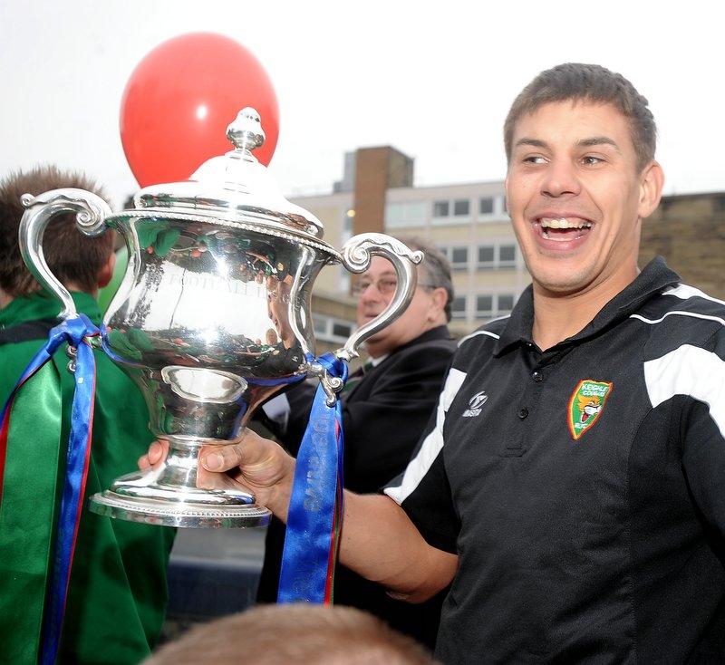 Keighley Cougars skipper James Feather proudly holds the trophy aboard the open-top bus.