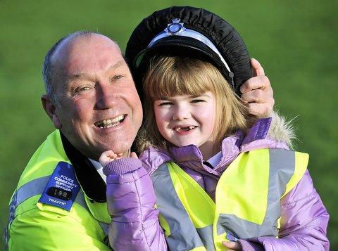 Money from the sale of assets seized from criminals is helping keep children safe in Bradford with the purchase of 500 fluorescent jackets. 
PCSO Denis Bennett with seven-year-old Ellie-Mai Roberts, one of the first recipients of a jacket.