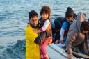 A Human Relief Foundation aid worker carries a small child from a boat arriving in Kos