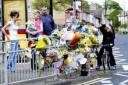 Residents look at the floral tributes to bike rider Anthony Pearson, killed on Broadstone Way, Holme Wood
