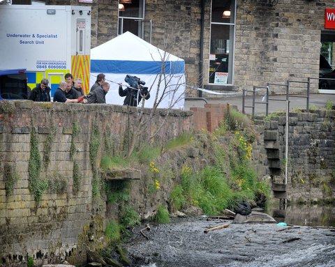 Police officers and the underwater search team view a black bag in the River Aire at Shipley.