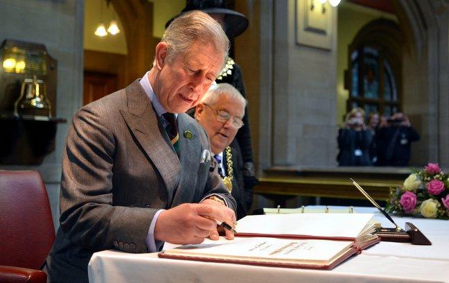 Prince Charles signs the visitors book at City Hall.
