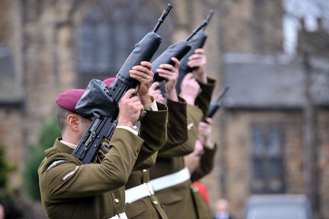 An honour guard fires a salute following the funeral of Private Martin Bell