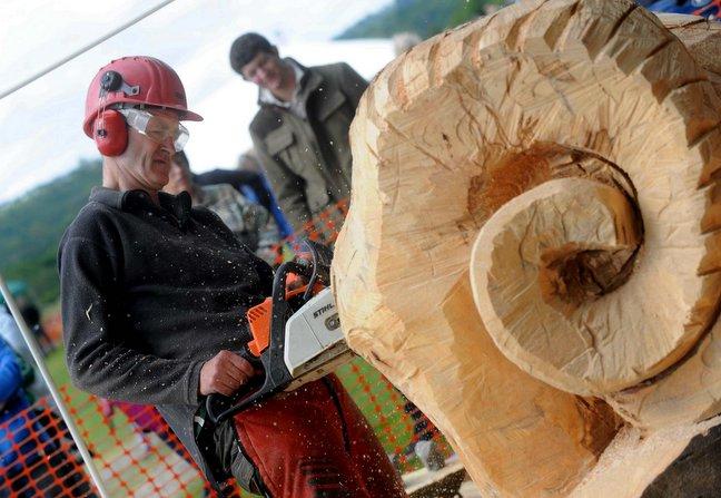Shane Green works on a wooden sculpture of a ram with a chainsaw.