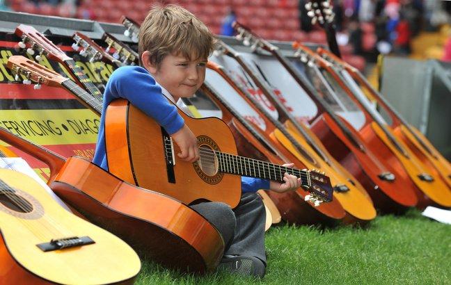 Nick Hutchinson, from Burley Oaks Primary, sits playing, surrounded by his classmates guitars.