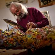 Buddy Brook at work in his studio. His wood carvings reflect various artistic styles