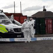 Police in forensic gear are investigating an incident on Thornbury Road, Bradford