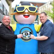 Rate My Takeaway’s Danny Malin pictured alongside Bradford BID's Jonny Noble and the soapbox race's official mascot