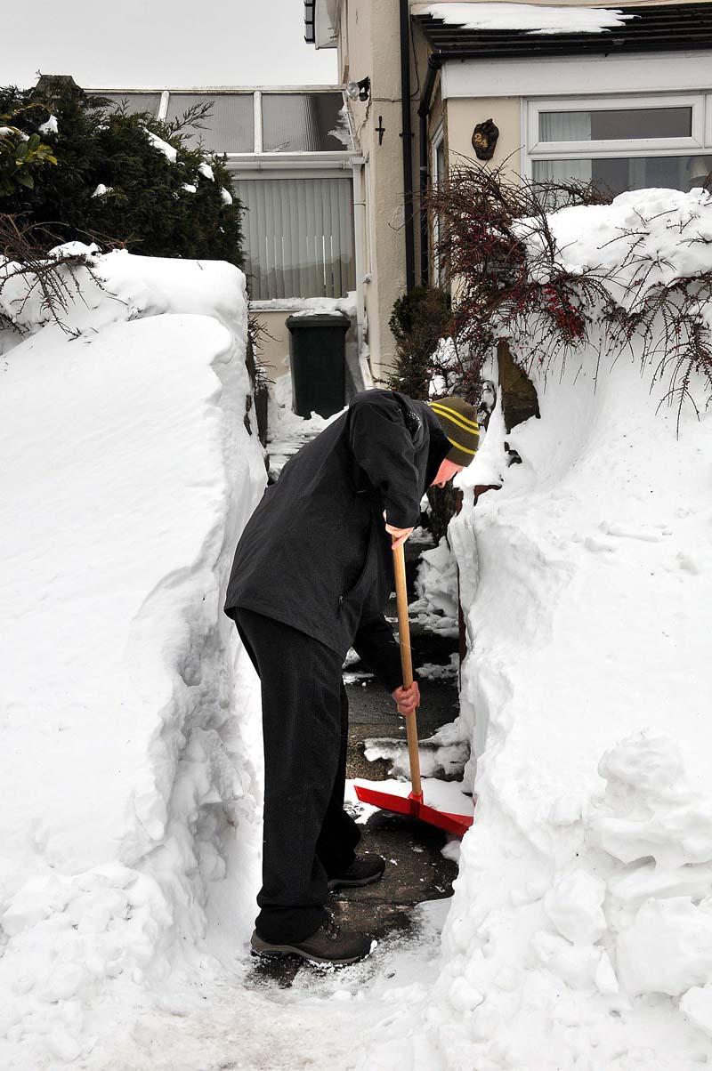 A resident of Crack Lane, Wilsden, cuts a path through the snowdrift to get to his house