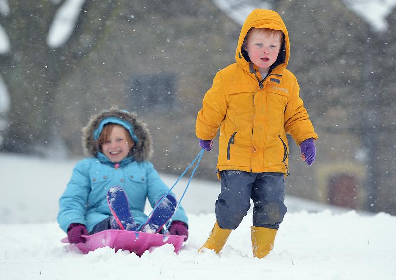 Grace catches a lift from her brother Ted Atkinson as they enjoy the snowy weather at Ilkley's Riverside Park