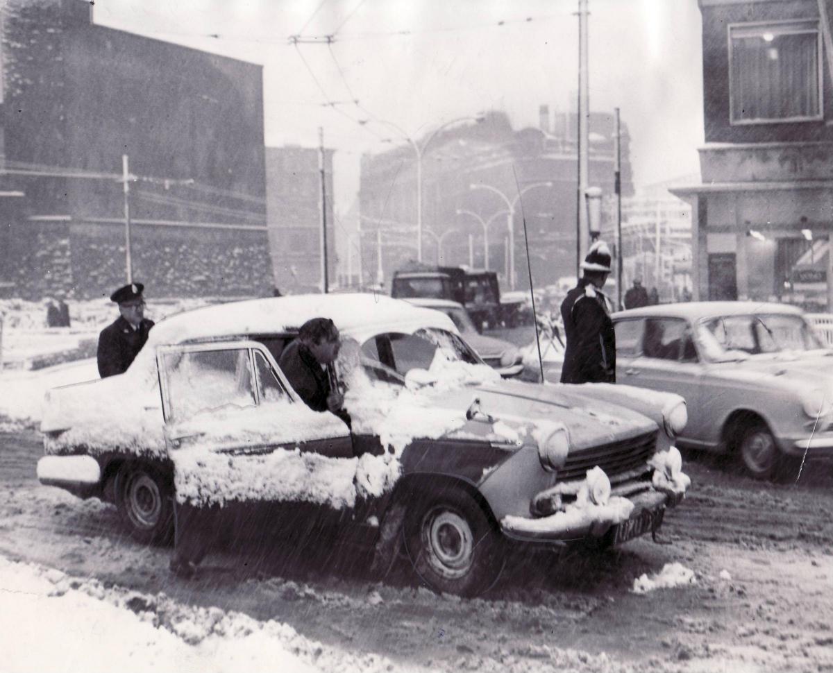 Police officers help move a car stuck in snow in Bradford city centre in 1965
