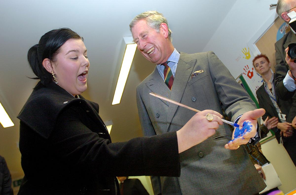 Samantha Burns paints the Prince's hand blue so he can do a hand print for the Cornerstone Centre wall