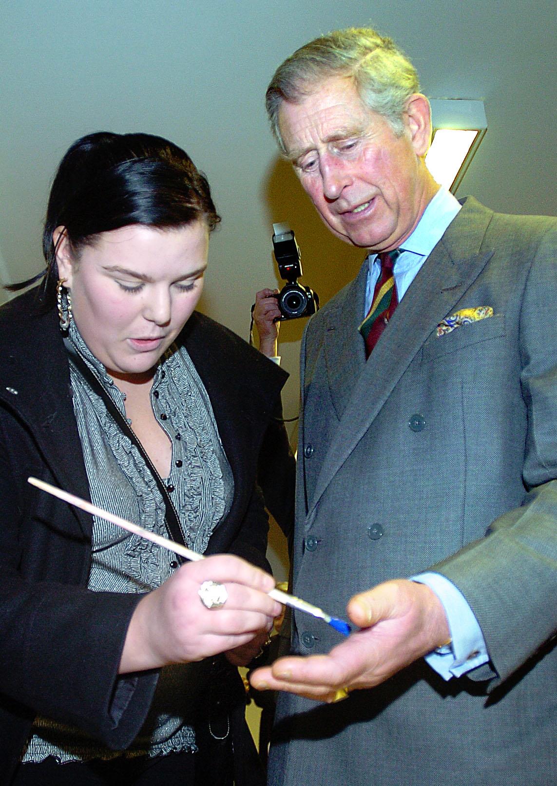 Samantha Burns paints the Prince's hand blue so he can do a hand print for the Cornerstone Centre wall