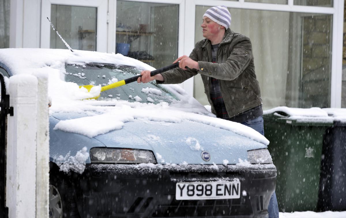 Paul Maxwell clears snow from a car in Shipley