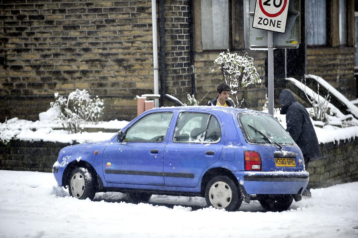 Two lads clear snow from a car