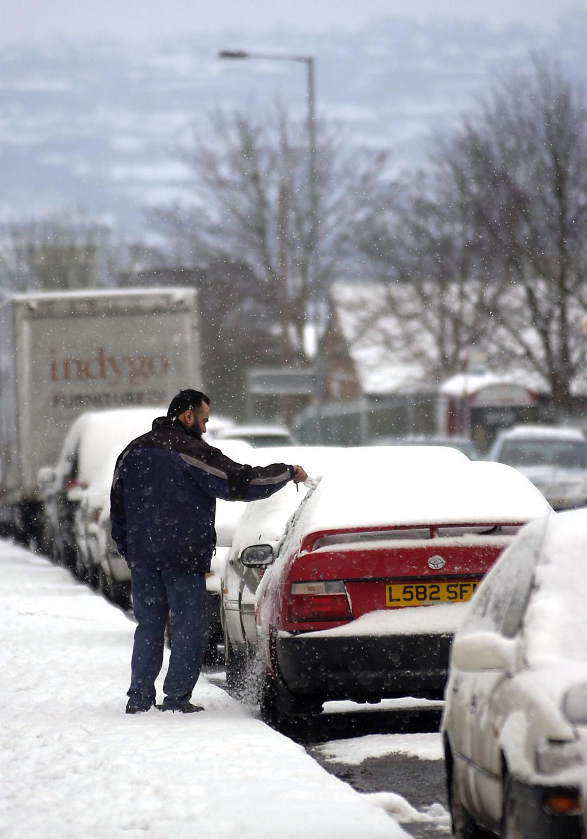 A driver clears snow from his car in Otley Road, Bradford.