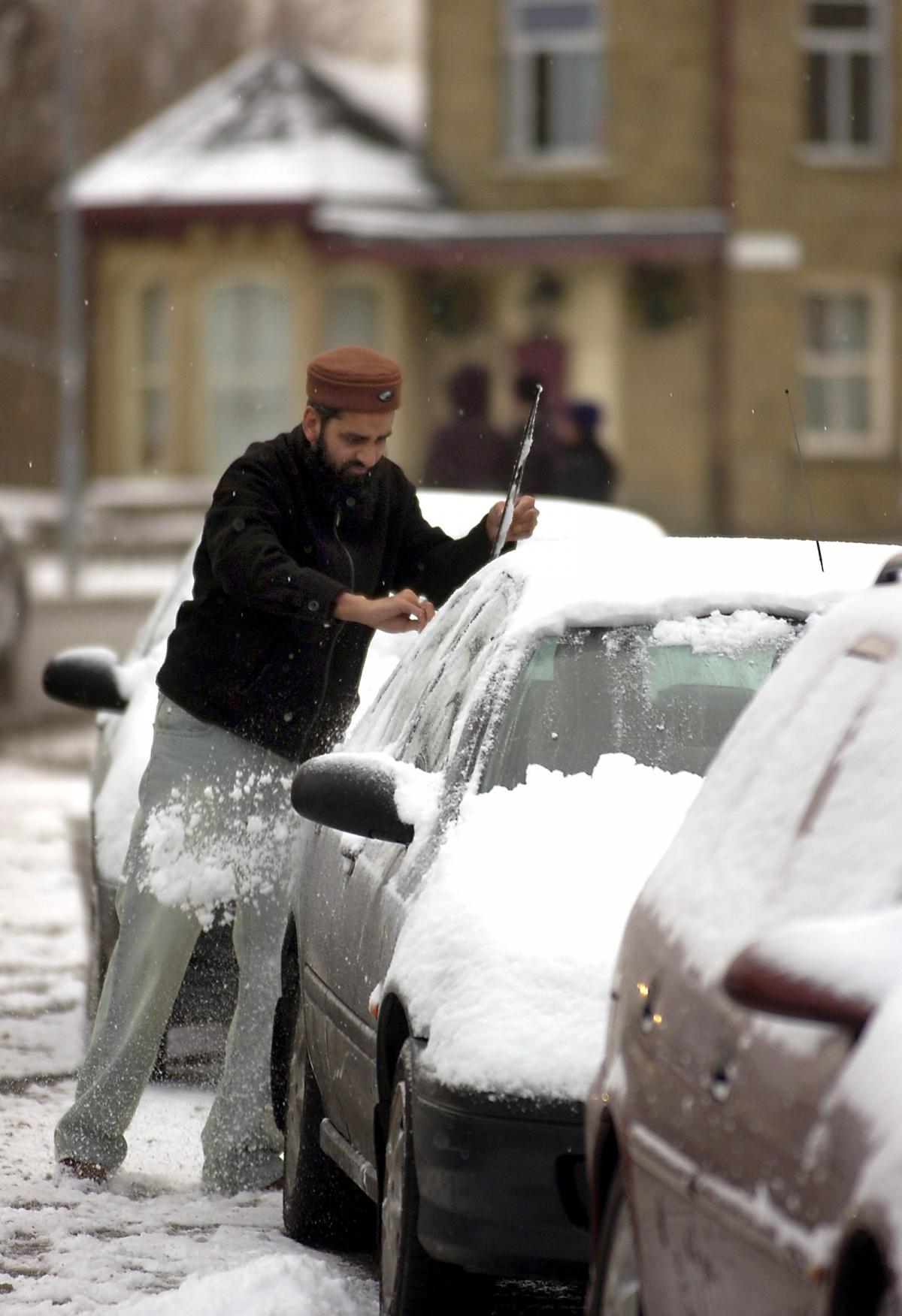 A driver clears his windscreen in Otley Road, Bradford.