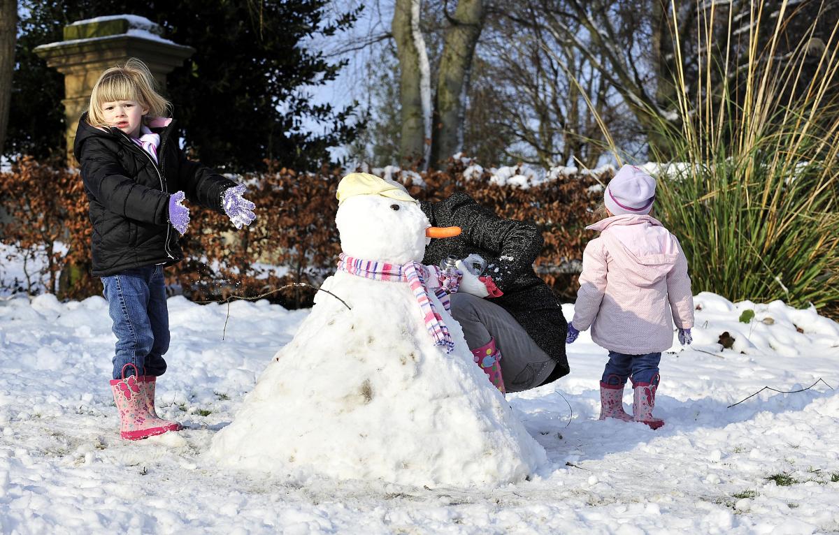 Chloe Drake, Kelsie-Mae Drake and Charlie Buckroyd build a snowman in Northcliffe Park, Shipley.