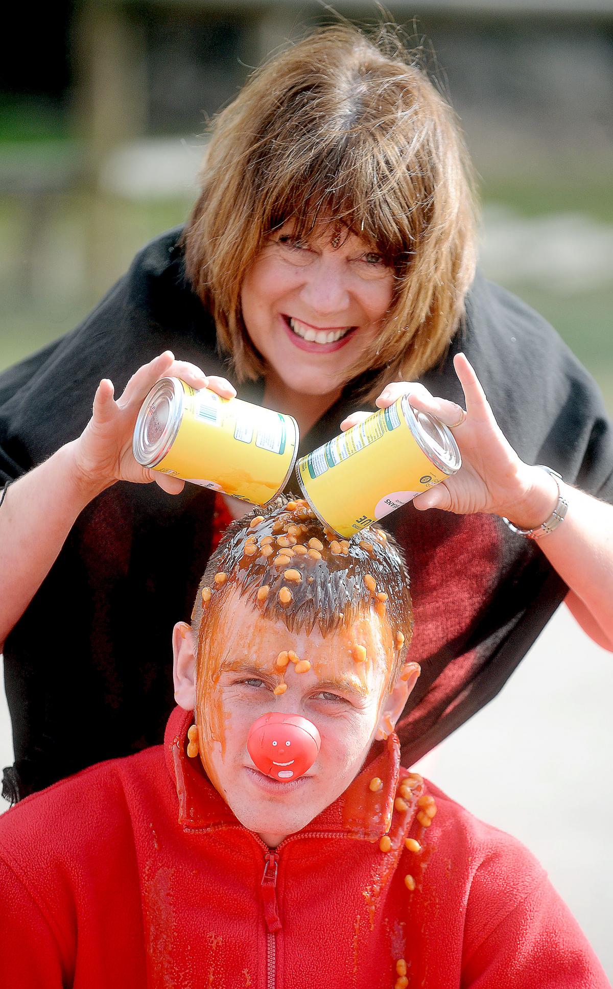 Nancy Hutchinson pours beans over Karl Illingworth's head to raise money for Comic Relief as part of the Red Nose Day activities at Heaton St Barnabas School.