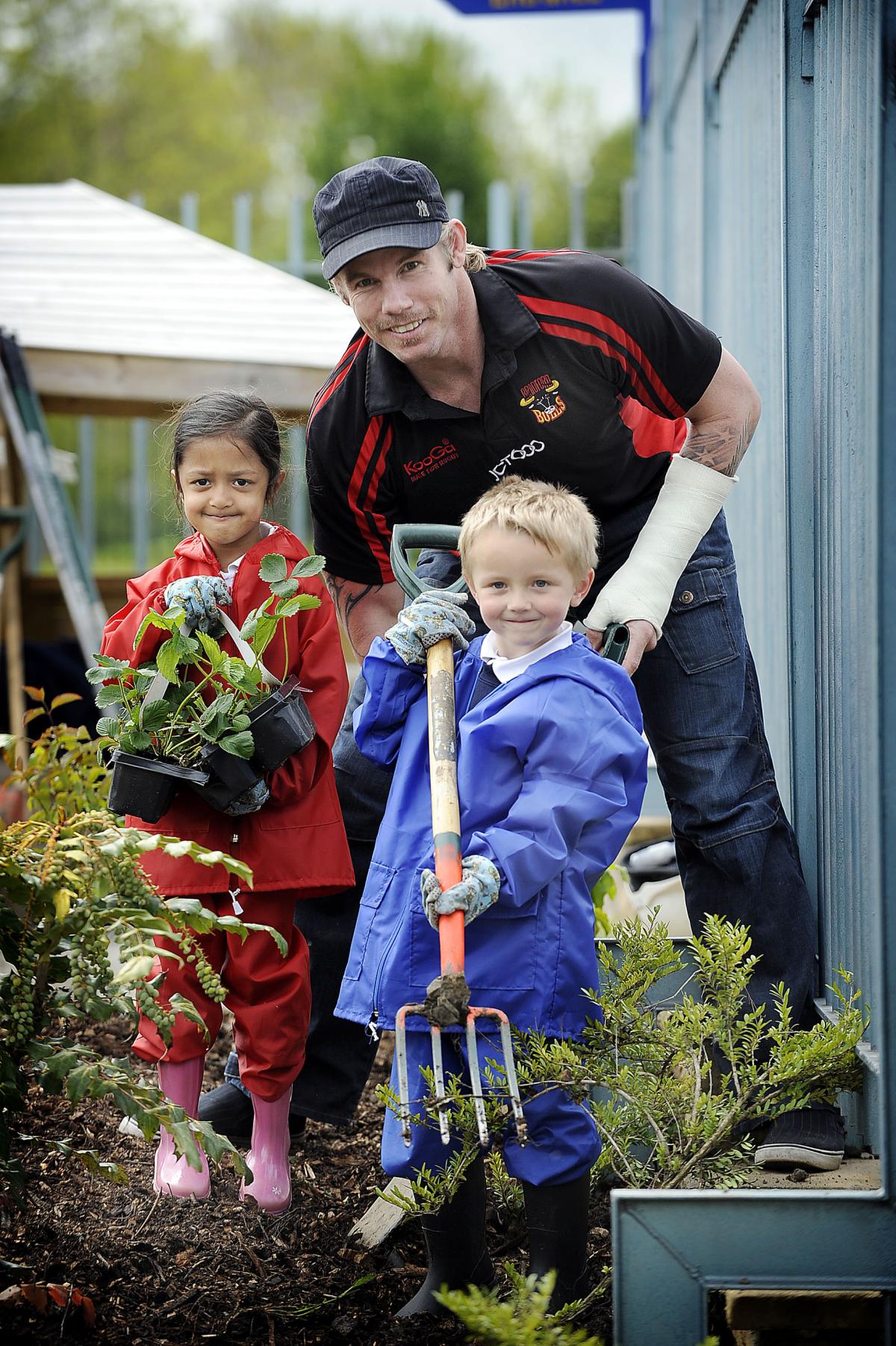 Bradford Bulls star Glen Morrison helps St Oswald's Primary School pupils Aliya Khan and Connor Jones keep up with jobs in the garden created for them by Yorkshire Water staff.