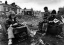Children sitting on old car seats reading comics - one of the street scenes in Life Goes On. Images: Ian Beesley