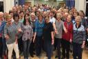 Members of The Skipton Choir  in full voice, with conductor  David Weale in their midst