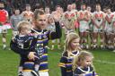 Bulls players look on as Rob Burrow, pictured with his children Macy, Maya and Jackson, acknowledges the crowd in the friendly against Leeds at Emerald Headingley   Picture: Dave Howarth/PA Wire