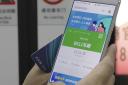 A passenger holds up a green 'free to travel' pass on their phone on a subway train in Wuhan. Picture: AP Photo/Olivia Zhang