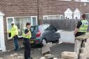 A structural engineer and police officers survey the scene of a crash on Rhylstone Gardens, Bradford