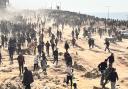 Palestinians wait for humanitarian aid on a beach in Gaza City (Mahmoud Essa/AP)