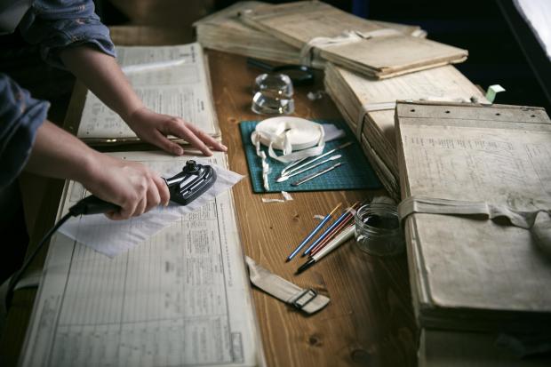 Bradford Telegraph and Argus: Emily Briffet, a Findmypast conservation technician, repairing damage to a page.