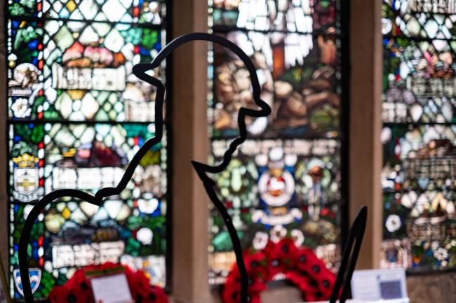 A statue of a soldier stands in front of Bradford Cathedral’s World War I window.