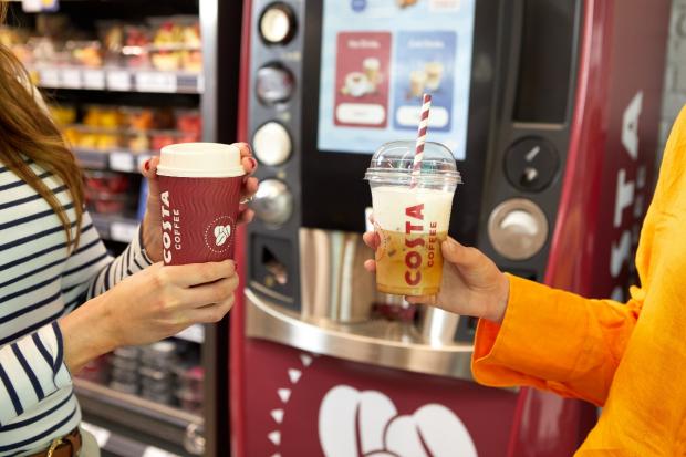 Bradford Telegraph and Argus: One person holding a hot drink (left) and another person holding a cold drink (right) in front of a new Costa Express machine (Costa Coffee)