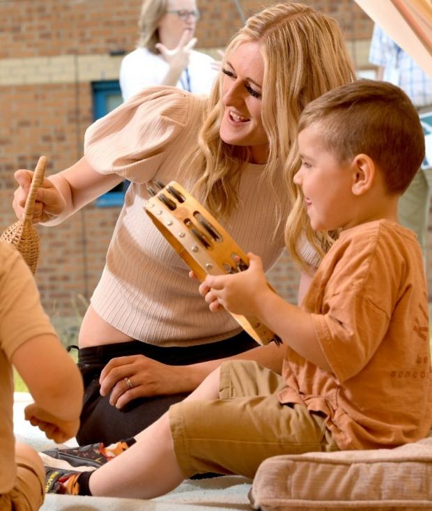 Bradford Telegraph and Argus: Childcare and education manager Alison Sturrs works with a child on using a tambourine.