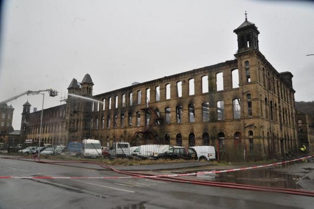 Bradford Telegraph and Argus: Firefighters damping down the mill after the huge blaze