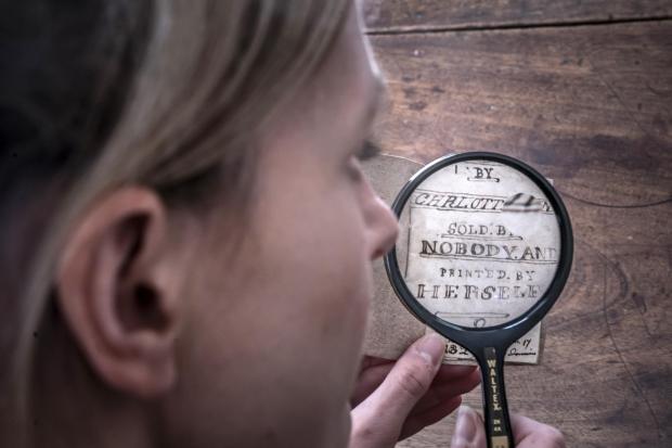 Bradford Telegraph and Argus: Curator Sarah Laycock uses a magnifying glass to inspect the manuscript. Picture: PA