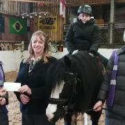 Carla Weatherall and son Ryan present a cheque to Haworth Riding for the Disabled Association. Image: Funeral Partners