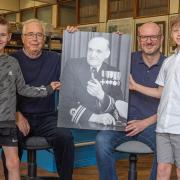 Three generations of his family hold a portrait of Robert Turner