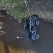 photographs show a 4x4 being recovered from a swollen river following the death of three men who were 'swept away' by floodwater.