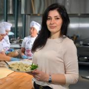 Oksana Kateryniak holds a plate of freshly made goods in the Multi Cook kitchen