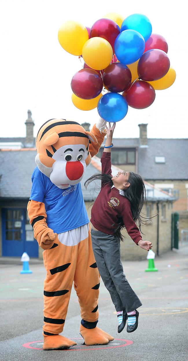 Eshal Ahmed tries to reach balloons being released by Tigger, visiting Horton Grange Primary School to help at a balloon release for Refugee Week