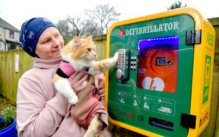 Katie Lloyd and cat Dijon by the new defibrillator