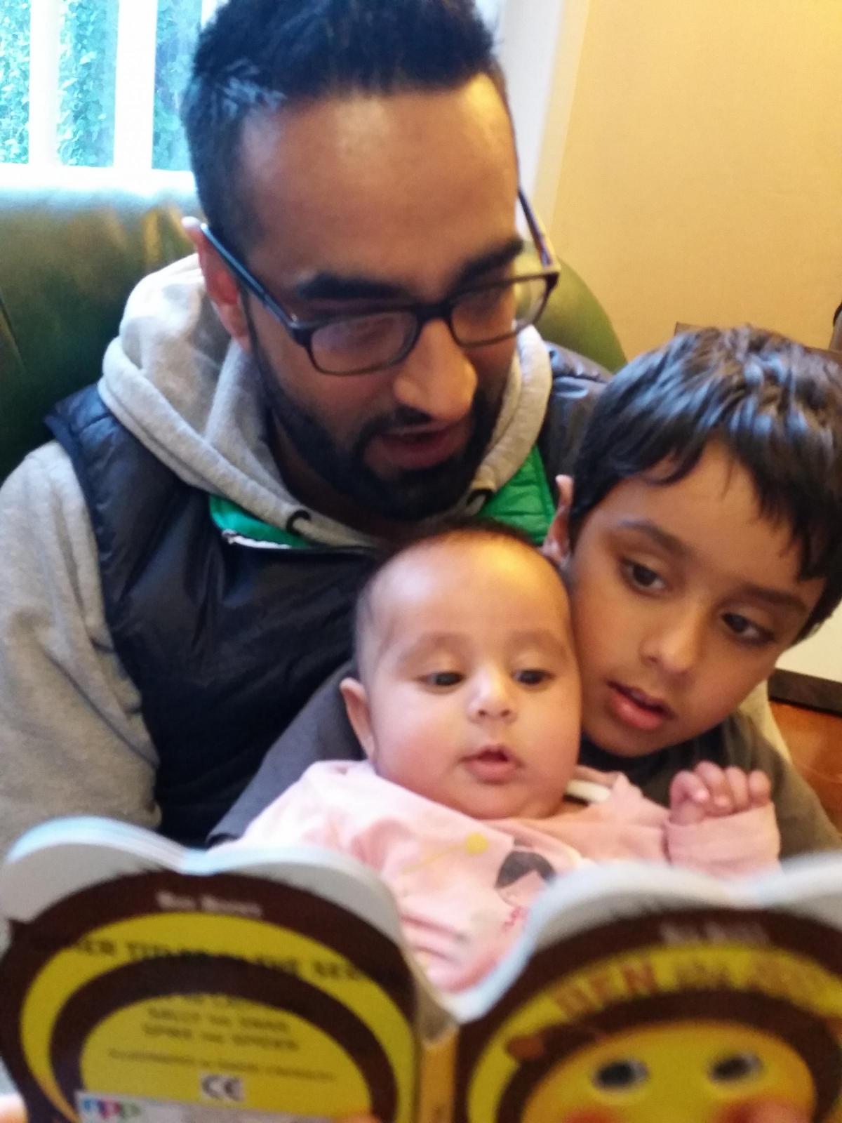 Imran Hafeez, Manager of the National Literacy Trust Hub in Bradford reading to his 3-month-old daughter, Kenzah and son Sudais, aged 5. Their favourite book is Dogger by Shirley Hughes.