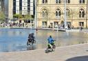 Two men ride through City Park in Bradford on dirt bikes as bemused children watch on